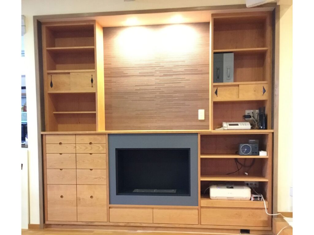 暖炉を中心に収納と照明を組み込んだ天然木のオーダー壁面収納
